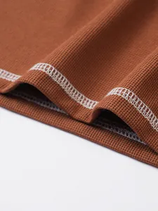 Close-up detail of waffle knit cotton fabric and white stitching on men's Henley shirt