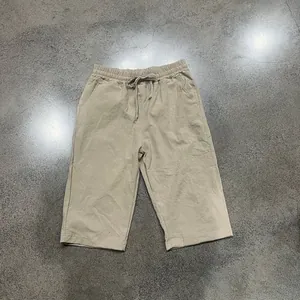 High-angle flat lay view of men's casual beige linen cropped pants with drawstring