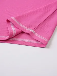 Close-up of pink waffle-knit fabric and white double-stitching on casual T-shirt hem.