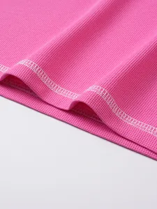 Detailed macro view of pink waffle knit texture and stitching on casual men's Henley shirt