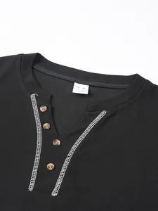 Close-up detail of black men's Henley shirt with white contrast stitching and brown buttons