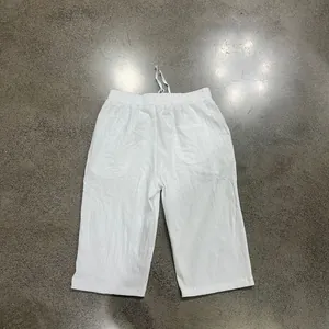 Detailed flat lay view of white lightweight linen 3/4 length men's loose beach shorts
