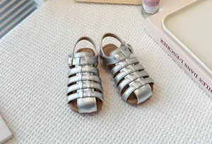 Close-up of children's silver hollow-out woven Roman sandals with soft soles