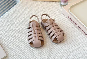High-angle shot of girl's pinkish-beige woven caged Roman sandals with soft soles