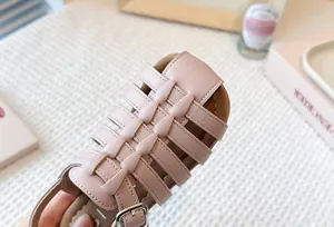 Close-up detail of the woven leather texture on girls' pink Roman beach sandals