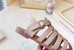 Detail of pink woven hollow Roman sandals with adjustable buckle strap