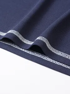 Close-up of navy waffle knit fabric and white double-needle stitching detail on shirt hem