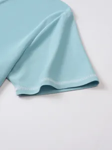 Close-up detail of light blue textured cotton Henley shirt sleeve with white stitching