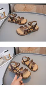 Detailed view of brown girls' gladiator sandals with gold buckles and beige footbeds.