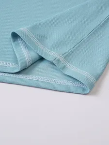 Detail of light blue waffle-knit fabric and double-stitched hem on men's Henley shirt.