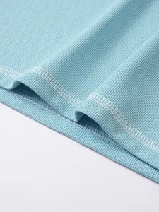 Close-up of light blue waffle fabric texture and stitching on men's Henley shirt