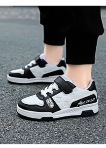 Close-up of black and white children's leather sneakers with Velcro straps and laces.