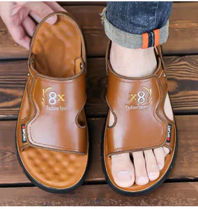 Detailed view of men's brown leather sandals worn on a rustic wooden floor