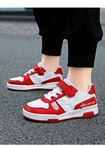 Detailed view of red and white kids' sneakers with Velcro straps and leather finish