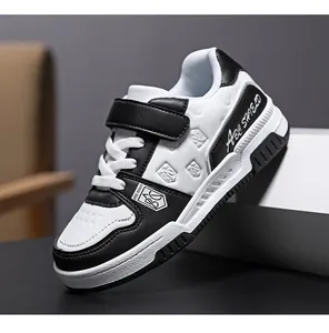 Detail view of black and white kids sneakers with velcro strap and leather finish