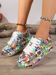 Detailed view of women's colorful graffiti print sneakers with white laces on wooden floor