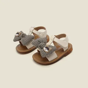 Detailed view of cream baby girls sandals featuring a plaid bowknot and cute cartoon accent