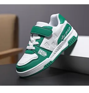 Detail view of durable green and white boys' sneakers featuring Velcro straps and shield logo