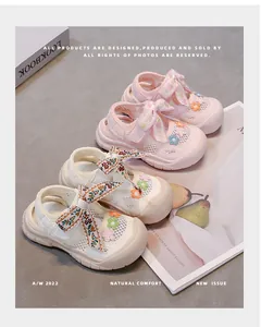 Primer plano de sandalias de malla transpirable para niña con lazos florales rosa