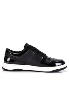 Detail shot of black genuine leather low-top sneakers with patent leather accents.