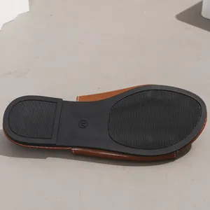 Detail view of the non-slip black sole of a tan women's flat sandal, size 37