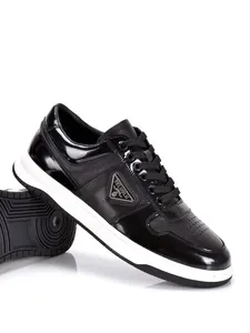 Detail view of men's black leather sneakers with white sole and lace-up closure
