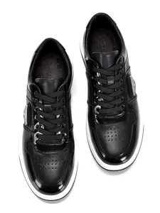 Top view of black leather low-top sneakers showing glossy and matte textures in detail