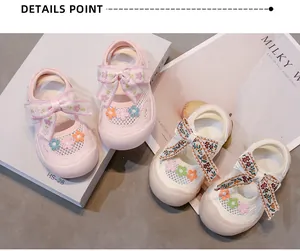 Primer plano de sandalias de malla para niña con bordado floral y detalles de lazo decorativo