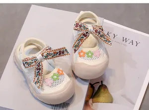 Detalle de sandalias de malla para niña con lazo bordado floral y flores aplicadas