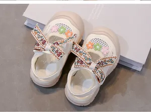 Primer plano de sandalias de malla blanca para niñas con bordado floral y lazo