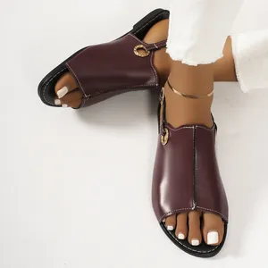 Close-up view of wine red flat sandals with metal ring detail on white background