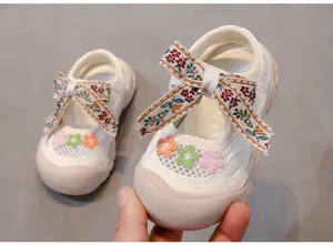Primer plano de sandalias blancas para niña con lazo bordado de flores y malla