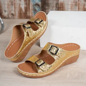Close-up detail of gold platform wedge sandals with crocodile texture and double buckles.