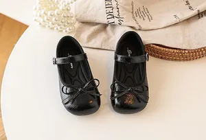 High-angle close-up of shiny black girls' Mary Jane shoes with elegant bow details