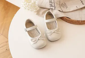 Close-up of elegant cream white girls' Mary Jane shoes with cute bow and buckle detail