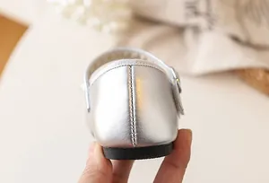 Detailed close-up view of the heel and stitching on silver girl's princess flat shoes