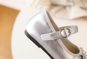 Detailed view of silver metallic Mary Jane shoe for girls featuring a buckle and bow.