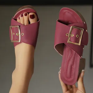 Detailed view of burgundy platform sandals with large gold buckle and chunky heel.