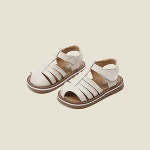 Detailaufnahme von süßen cremefarbenen Mädchensandalen mit weicher, rutschfester Sohle