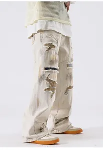 Vue latérale détaillée d'un jean baggy blanc cassé avec de fortes déchirures et patchs