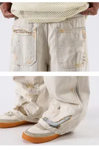 Détails déchirés et taches de peinture sur un jean baggy blanc cassé en gros plan
