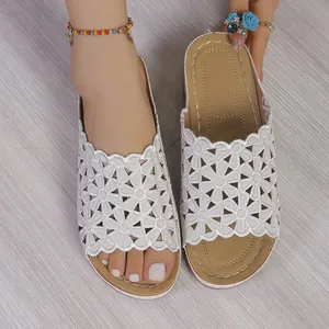 Primer plano de sandalias blancas bordadas con flores caladas para mujer en verano