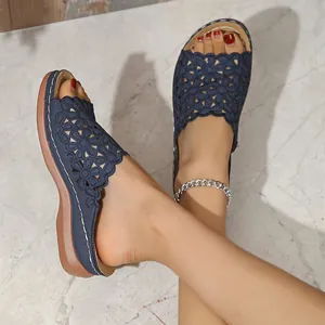 Detalle de sandalias azul marino con flores caladas y costuras blancas sobre mármol