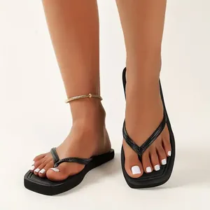 Detail view of stylish black thong sandals for women on feet, ideal for beach wear