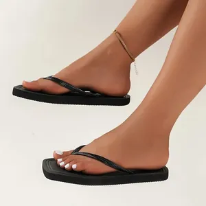 Elegant black thong flip-flops for women shown in a clean minimalist studio setting