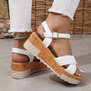 Primer plano de sandalias de cuña blancas con finas tiras trenzadas y una hebilla
