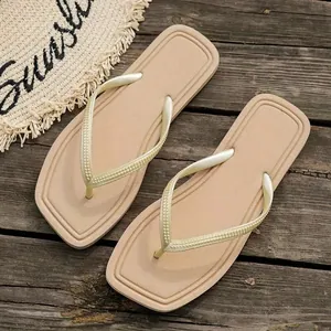 Top-down view of minimalist beige beach thong sandals on a rustic wooden background