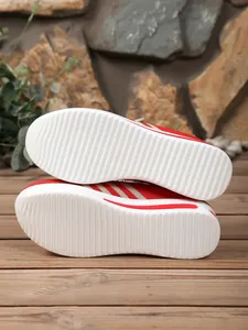 Detail of the white textured non-slip sole of the red wedge-heeled flying knit sneaker.