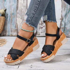 Primer plano de sandalias con cuña negras para mujer con tiras trenzadas y suela corcho.