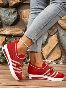 Detailed view of red and white striped fly-knit sneakers featuring a metallic chain accent